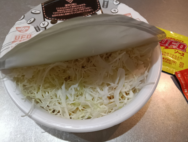 カップ焼きそばにキャベツを入れている画像